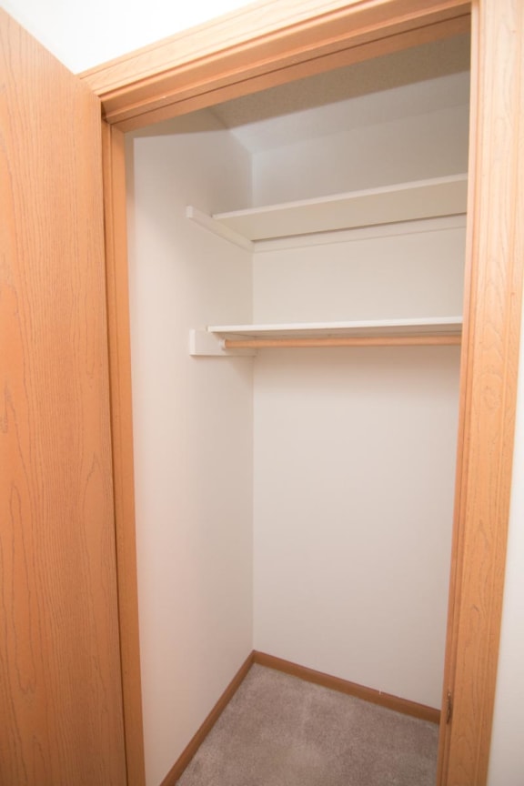 a walk in closet with a white wall and a shelf