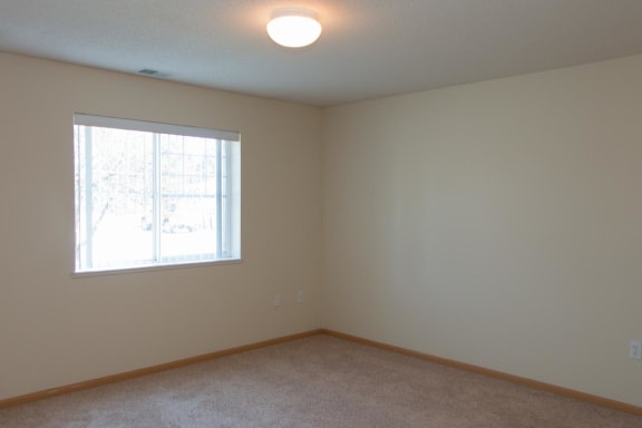 a bedroom with a window and a carpeted floor