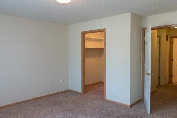an empty living room with an open door to a closet