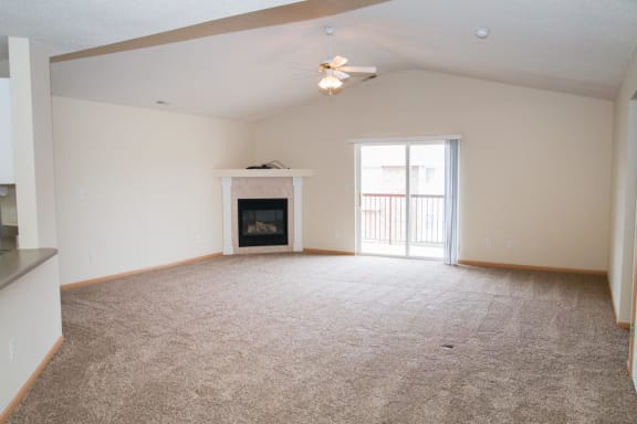 an empty living room with a fireplace and a ceiling fan