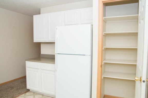 a white kitchen with a white refrigerator and shelves