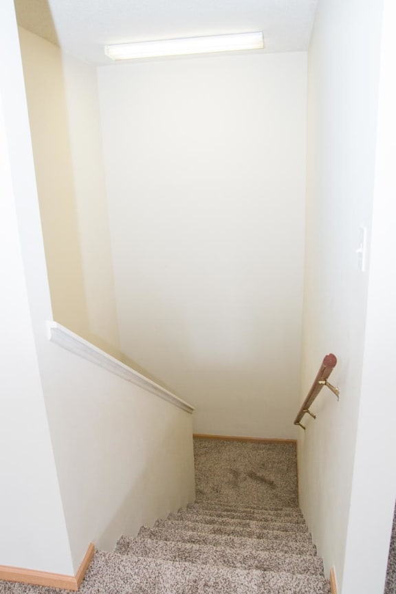 a small hallway with a landing with a chair and a white wall and a staircase