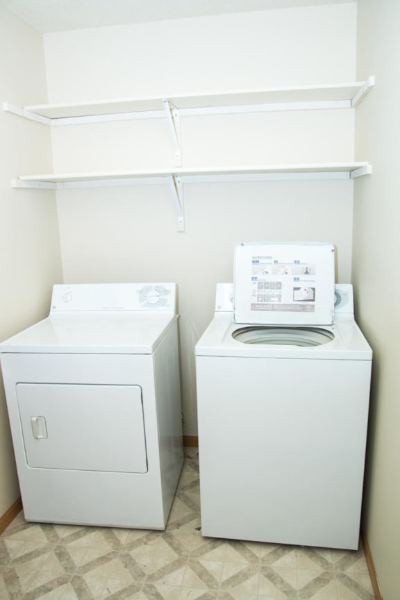 a washer and dryer in a laundry room with a shelf above it