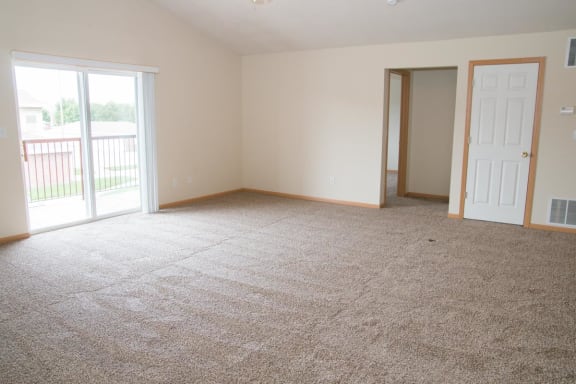 an empty living room with a door to a balcony