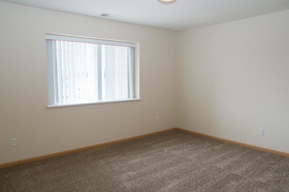 an empty room with a window and carpet
