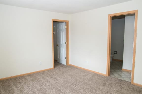 an empty living room with two doors and a carpet