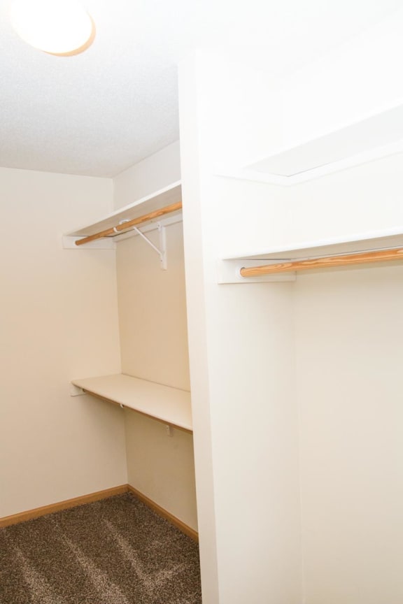 a walk in closet in an empty room with shelves