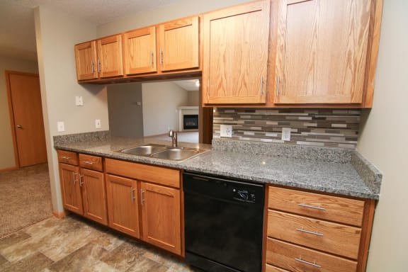 a kitchen with wooden cabinets and granite counter top and a black dishwasher