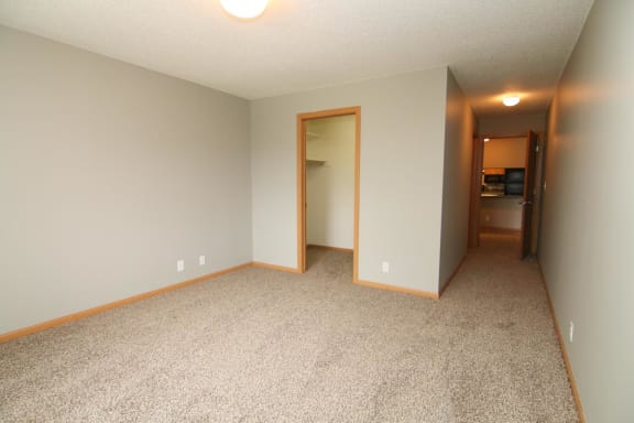 an empty living room with carpeting and a door to a bedroom