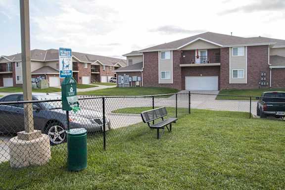 an off leash dog park with a bench and a trash can with doggy bags