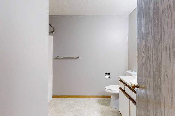 A bathroom with a toilet, sink, and a towel bar.