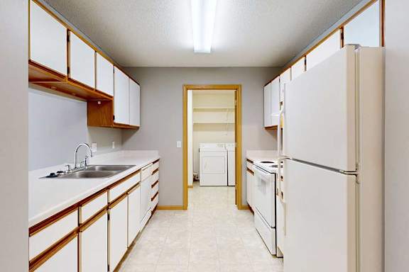 A kitchen with white appliances and wooden cabinets.