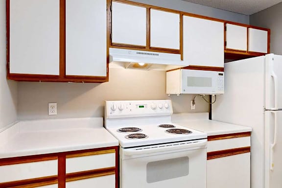 a white stove and oven in a kitchen with white cabinets and a white refrigerator