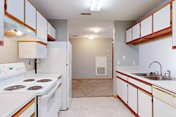 a galley-style kitchen with white appliances and cabinets