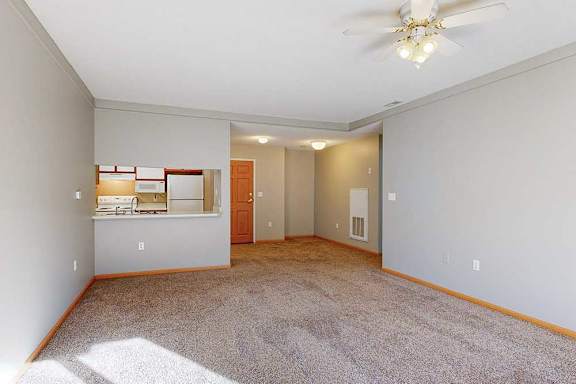 a spacious living room with a ceiling fan and carpeted floor