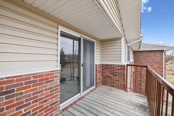A balcony with a glass door and a brick wall.