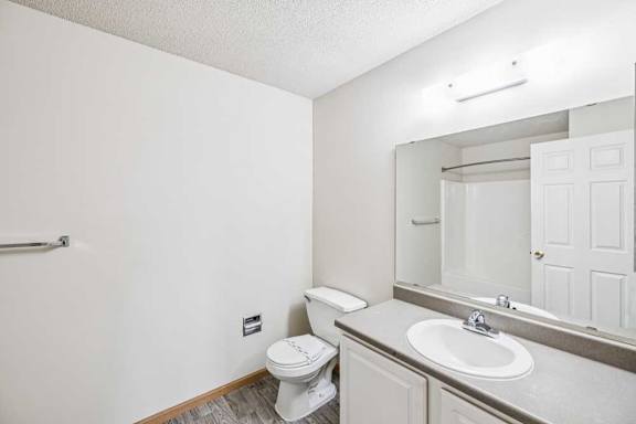 A white bathroom with a toilet, sink, and mirror.