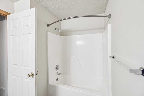 A white bathroom with a white tub and a white door.