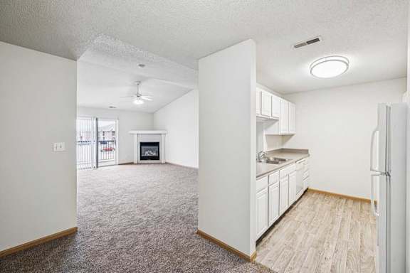 A spacious kitchen with white cabinets and a refrigerator.