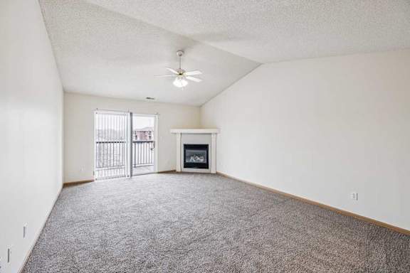 A spacious living room with a fireplace and a ceiling fan.