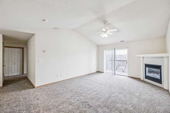 A spacious living room with a fireplace and a ceiling fan.