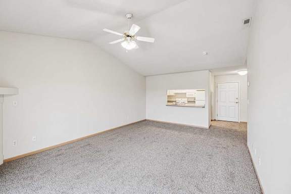 A room with a ceiling fan and carpeted floor.