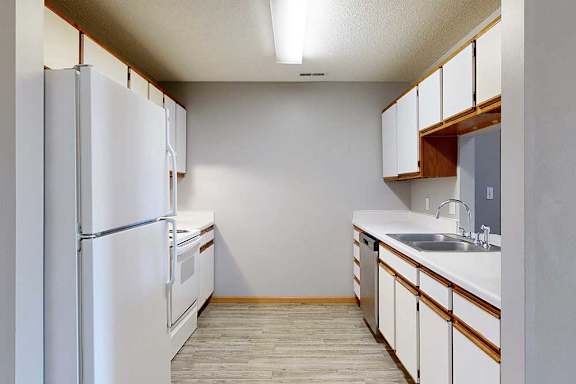 galley-style kitchen with a white appliances and white cabinets.