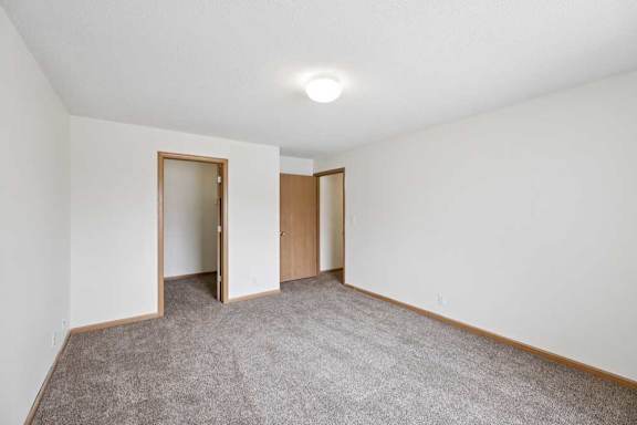 A room with carpeted floor and two doors.