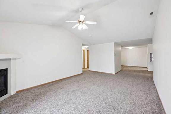 A spacious living room with a fireplace and a ceiling fan.