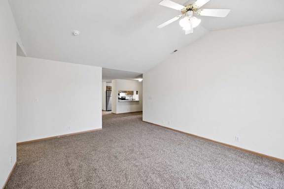 A spacious room with a ceiling fan and carpeted floor.