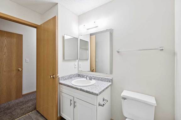 A bathroom with a toilet, sink, and mirror.