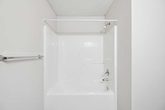 A white bathroom with a tub and a towel rack.