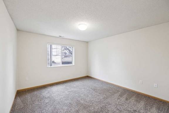 A room with a carpeted floor and a window.