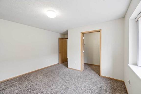 A room with a carpeted floor and two doors.