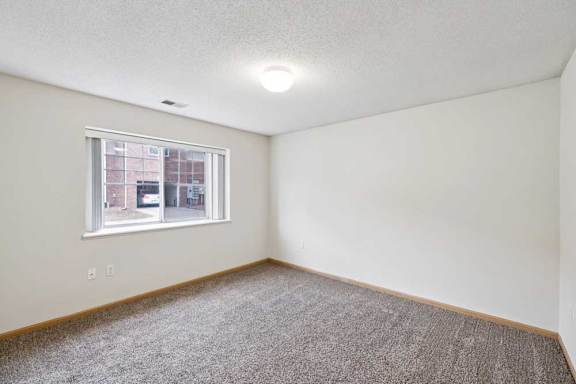 A room with a carpeted floor and a window.