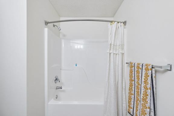 A white bathroom with a shower curtain and a towel hanging on the rack.