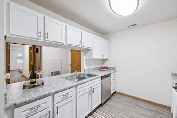 A kitchen with white cabinets and a grey granite countertop