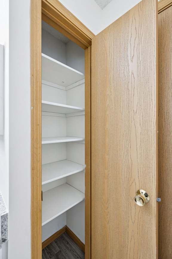 Empty linen closet with white shelves