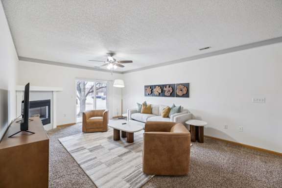 A living room with a fireplace, couch, two chairs, and a television.