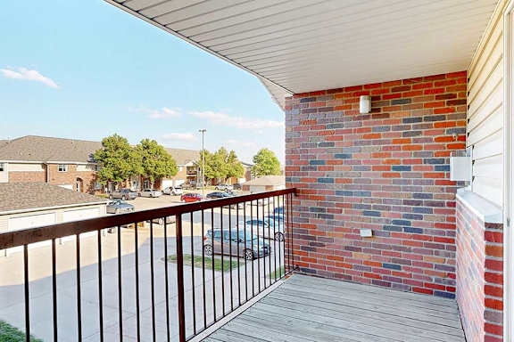 a balcony with a brick wall and a metal railing