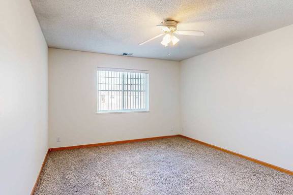 a carpeted bedroom with a ceiling fan and a large window