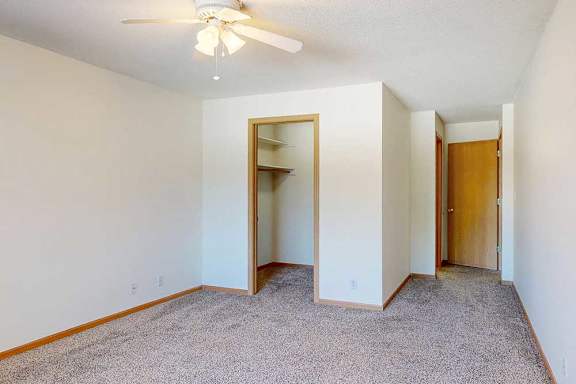 a carpeted bedroom with a walk-in closet, a ceiling fan, and an attached bathroom