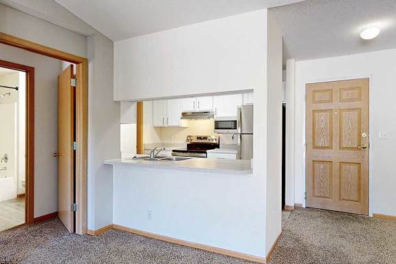 a kitchen with white cabinets and a windowed countertop that opens to the living room