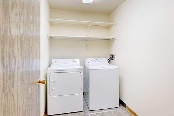 a laundry room with a full-sized washer and dryer and built-in storage shelving