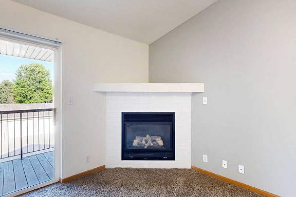 a living room with a gas fireplace in the corner with a built-in mantle