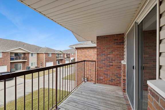 A balcony with a black railing and a brick wall.