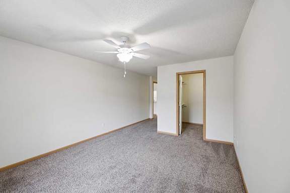 A room with a ceiling fan and carpeted floor.