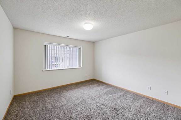 A room with a window and carpeted floor.
