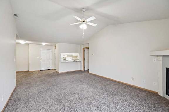 A spacious living room with a ceiling fan and carpeted floor.