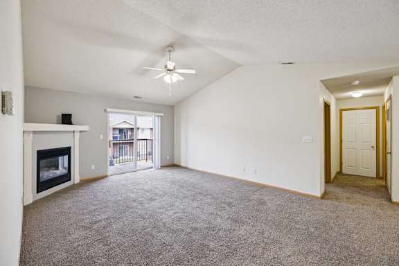 A spacious living room with a fireplace and carpeted floor.